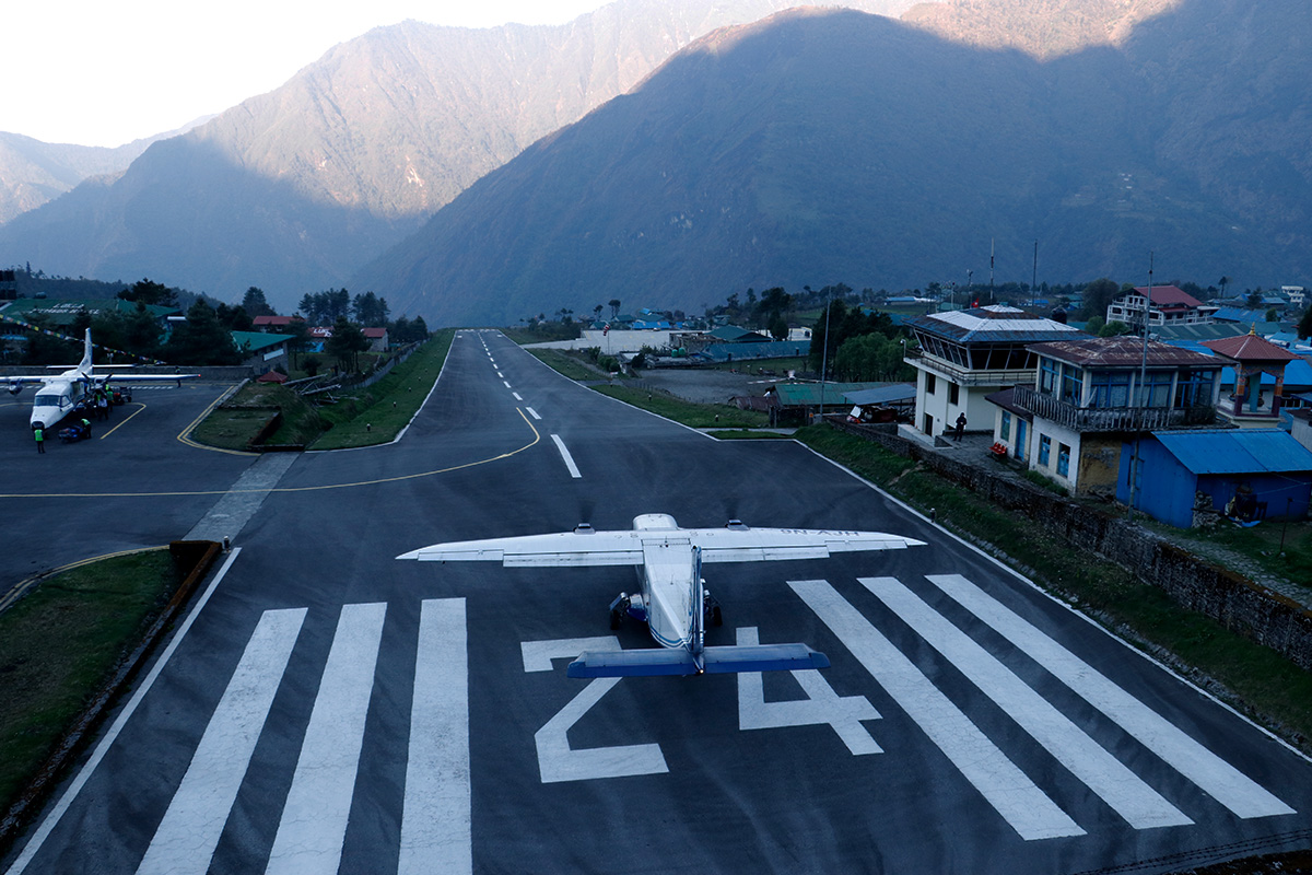 Aeroplane standing on Lukla airport and "24" written in the runway
